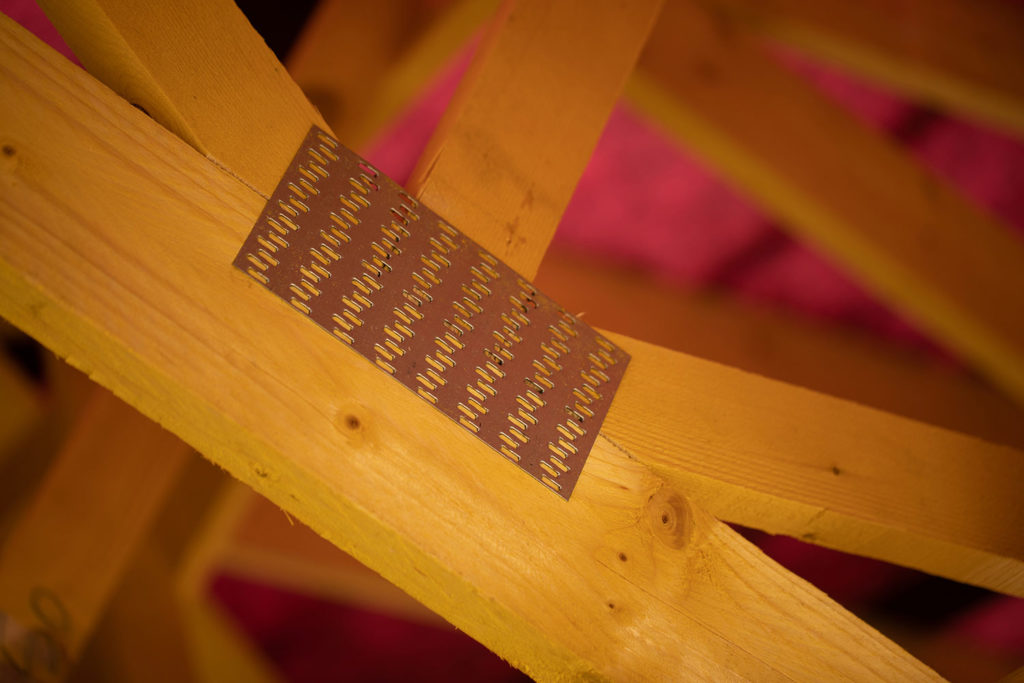 charpente fermette vue de près : zoom sur un connecteur métallique reliant les éléments en bois
